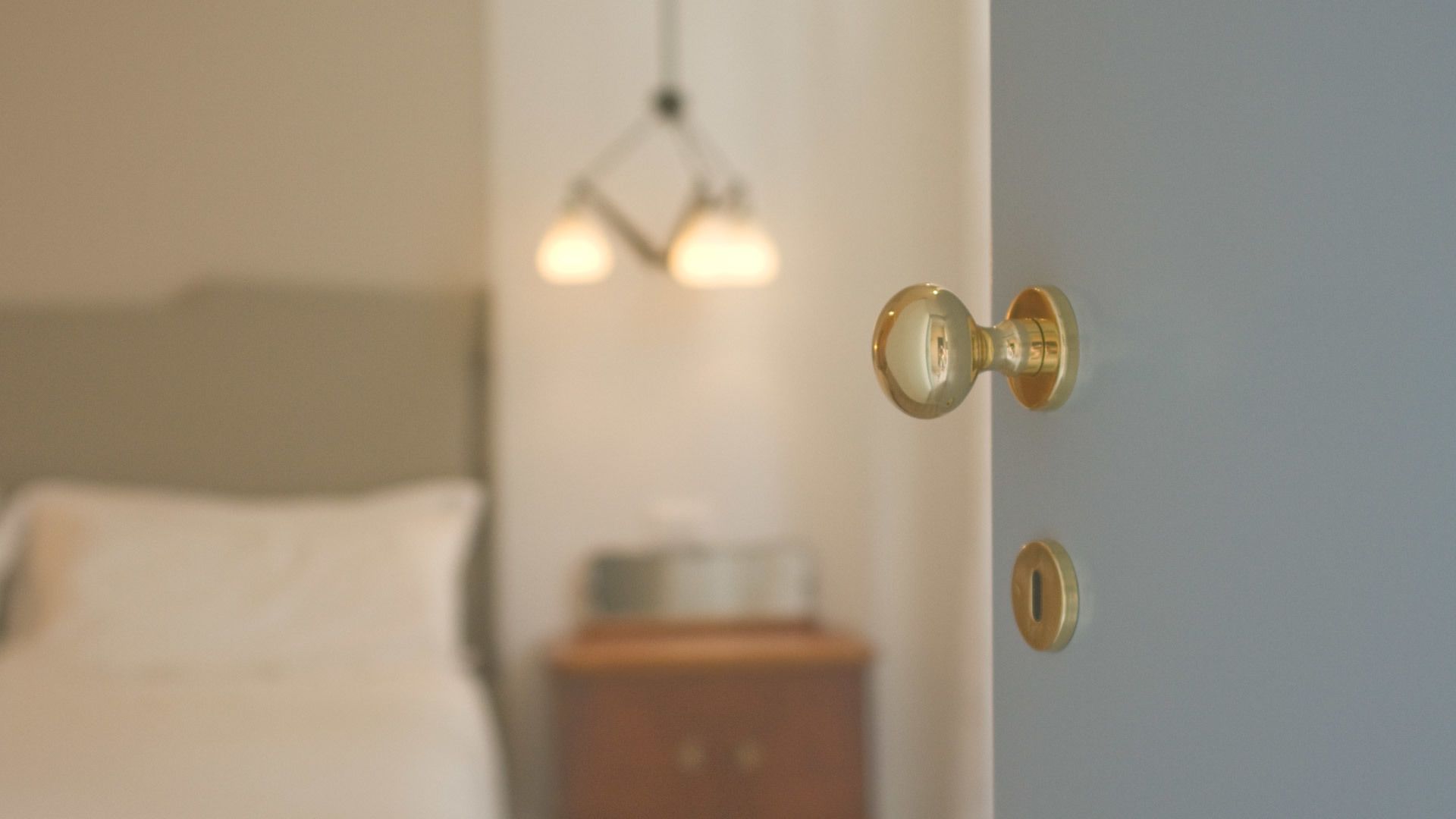 A bedroom with a bed, a nightstand, and a door with a brass doorknob.