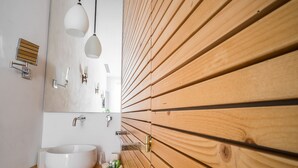 Ein modernes Badezimmer mit Waschtisch aus Holz, einer weißen Spüle und einem großen Spiegel.