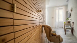 Ein Zimmer mit einer Wand aus Holzlatten, einem braunen Sessel, einem kleinen Tisch mit einer Pflanze und einem Stuhl.
