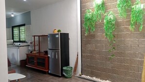 A modern kitchen with a refrigerator, stove, and dining area. - Villa Kota Bunga Anggrek (Cipanas)