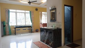 A spacious kitchen with a marble countertop, a ceiling fan, and a window with curtains. - Villa Kota Bunga Azalea (Cipanas)