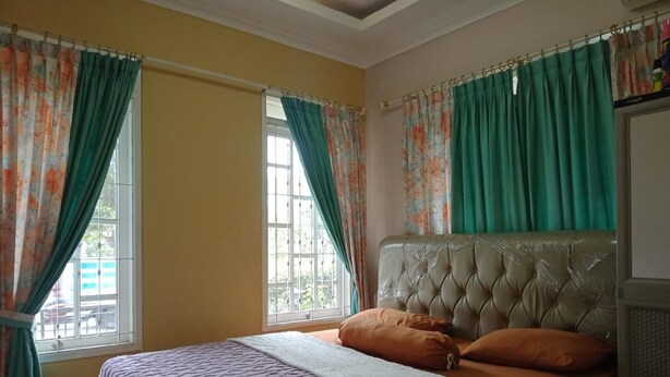 A bedroom with a bed, curtains, and a window. - Villa Kota Bunga Azalea (Cipanas)