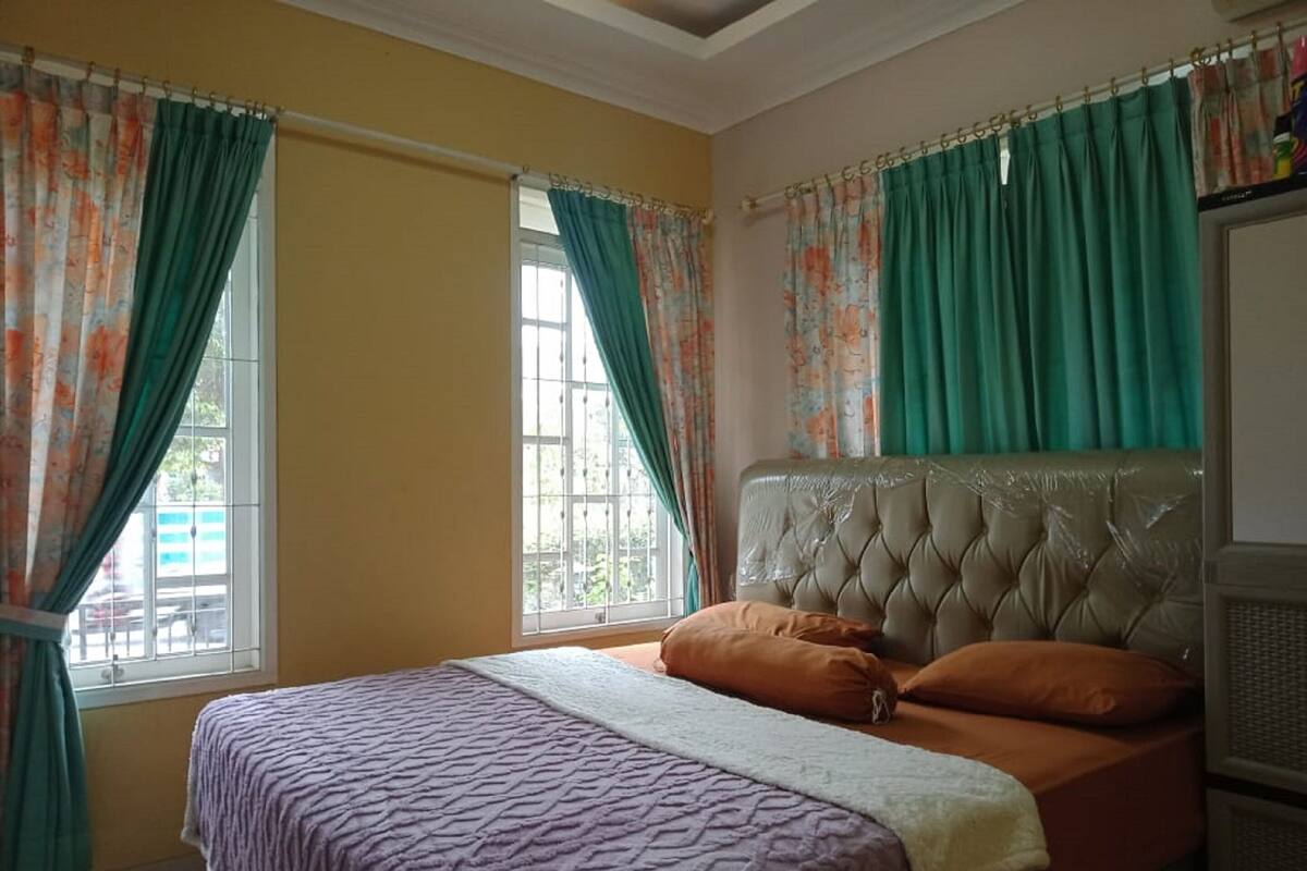 A bedroom with a bed, curtains, and a window.