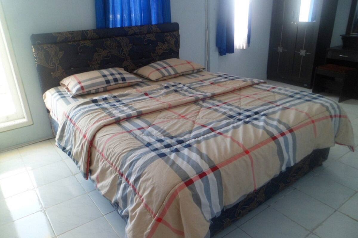 A bedroom with a bed, a headboard, and a wardrobe.