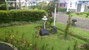 A garden with a lamp post, rocks, and a pathway. - Villa Kota Bunga Azalea (Cipanas)