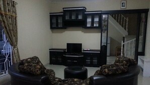 A living room with a sofa set, a TV, and a cabinet. - Villa Kota Bunga Cosmos (Cipanas)
