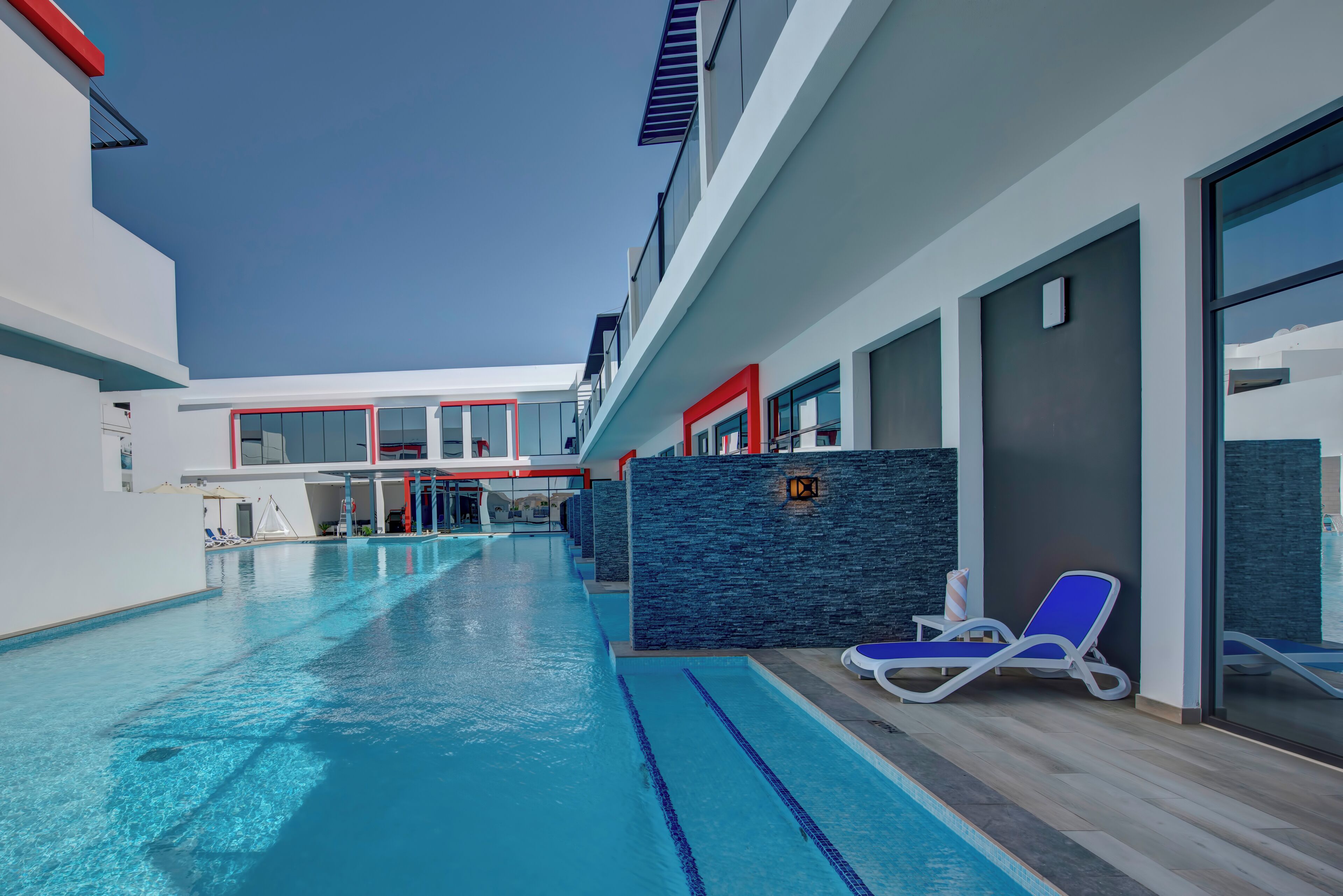 A modern indoor swimming pool with clear blue water, adjacent lounge areas, and a contemporary architectural design.