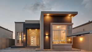 A modern building with a large glass window, a set of stairs leading to the entrance, and a flat roof. - KAY Homes (Ras Al Khaimah)