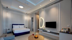 A modern hotel room with a large bed, a TV, a dining table, and a seating area. - KAY Homes (Ras Al Khaimah)