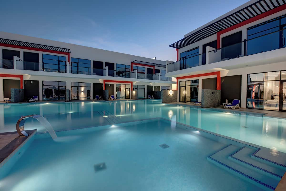 Un hotel moderno con una amplia piscina cubierta, varios balcones y un diseño contemporáneo.