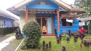 A two-story house with a blue facade, a tiled roof, and a front porch.