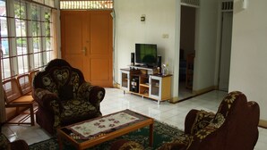 Una sala de estar con un sofá, sillones, una mesa de centro, un televisor y un aparador.