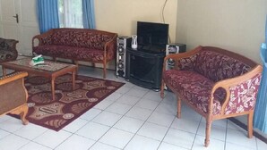 Una sala de estar con dos sofás, una mesa de centro, un mueble para televisor y una alfombra estampada.