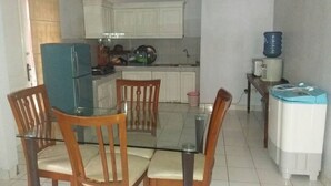 Una cocina compacta con armarios blancos, una mesa de comedor de vidrio y sillas de madera.