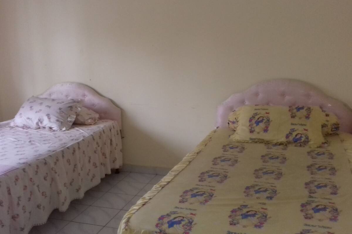 A small bedroom with two single beds, each with a headboard and a patterned bedspread.