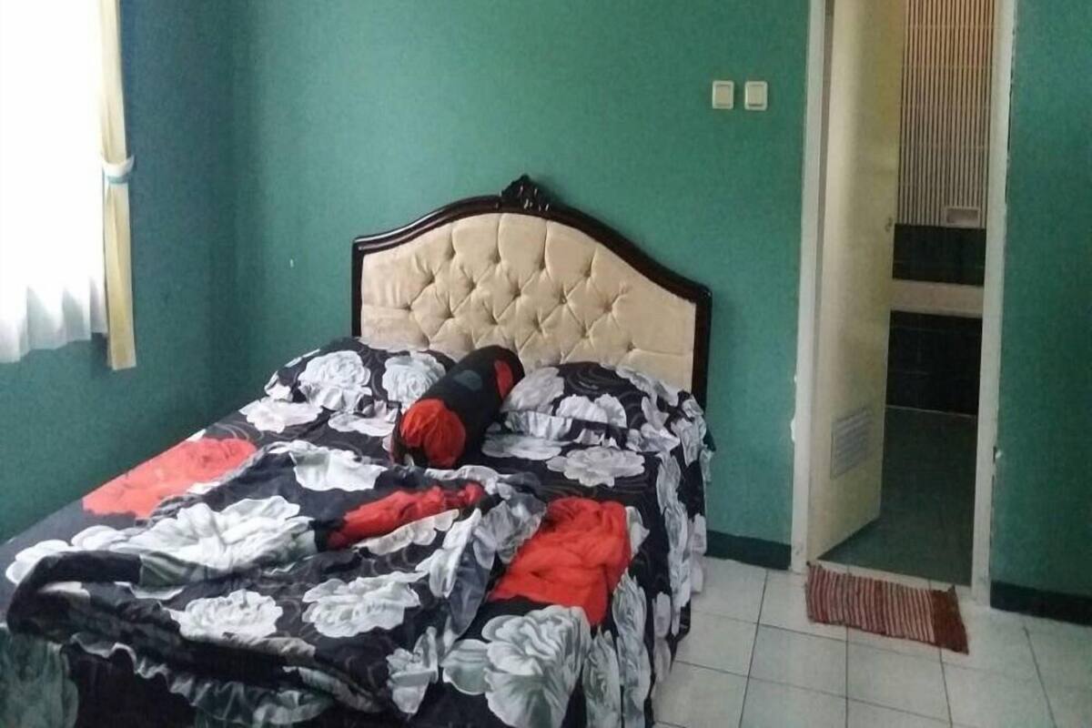 A bedroom with a bed, an air conditioner, a door, and a window.