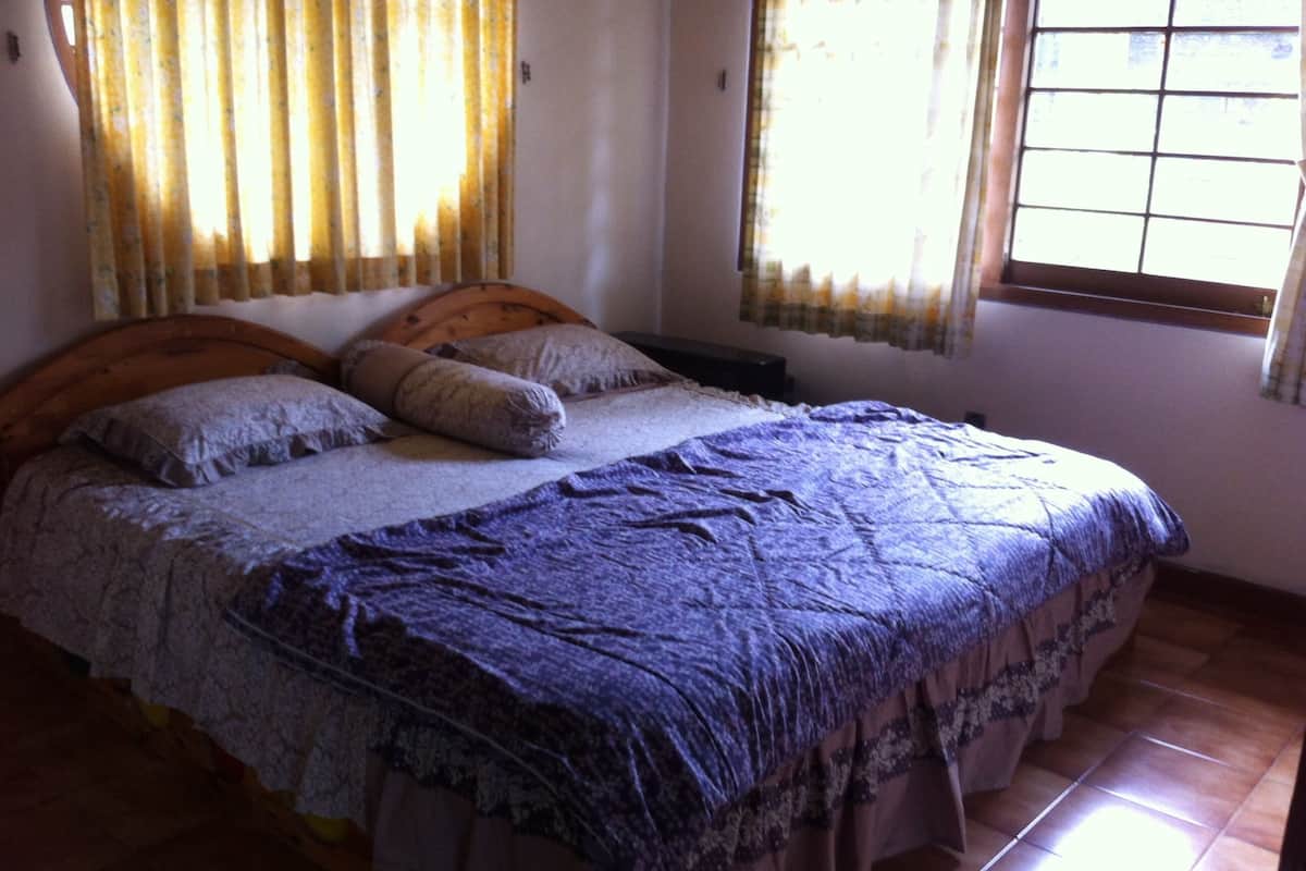 A bedroom with a bed, curtains, and a window.