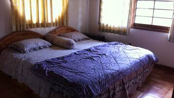 Un dormitorio con cama, cortinas y ventana.