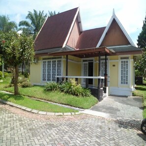 A two-story house with a tiled roof, a porch, and a paved driveway. - Villa Kota Bunga Teratai (Cipanas)
