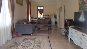 Ein Wohnzimmer mit zwei Sofas, einem Fernseher, einem Schrank und einem gemusterten Teppich.