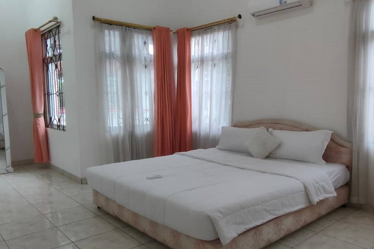 Un dormitorio con cama, cortinas y ventana.