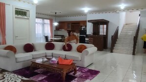 A living room with a sectional sofa, a coffee table, and a staircase. - Villa Kota Bunga Anyelir (Cipanas)