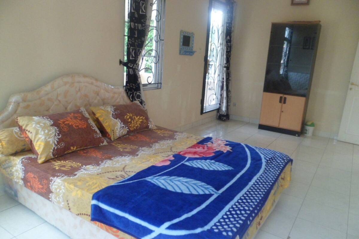 A bedroom with a bed, curtains, a wardrobe, and a window.