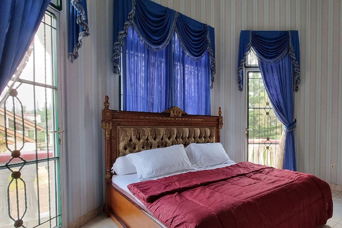 A bedroom with a wooden bed, blue curtains, and a view of the outdoors.