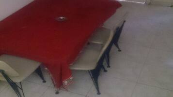 A dining table with a red tablecloth, four chairs, and a small decorative item on the table.