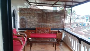 A balcony with a wooden bench, red cushions, and a patterned rug. - Villa Kota Bunga Vinca (Cipanas)