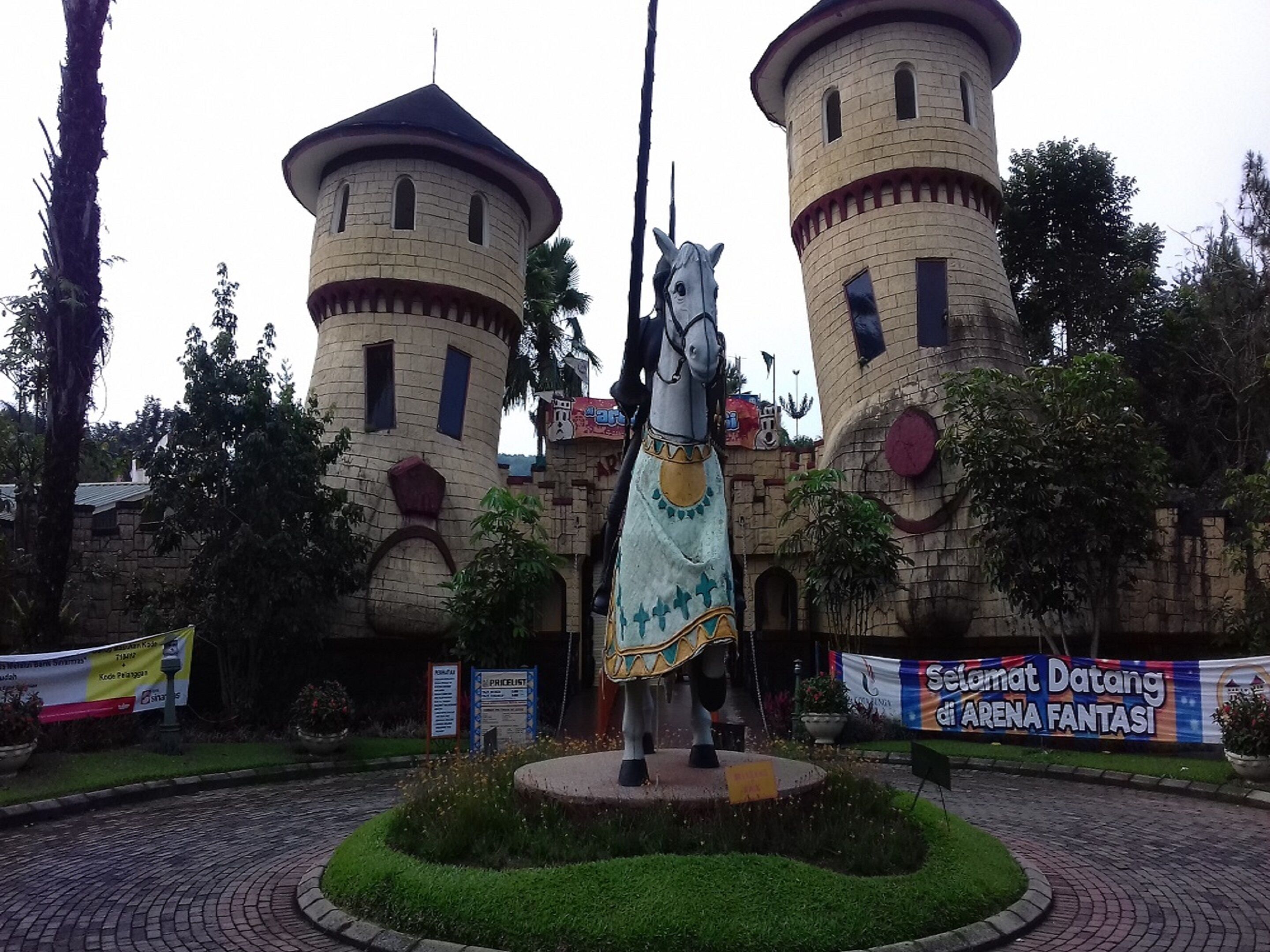 A castle-like structure with two towers and a statue of a horse in the center.