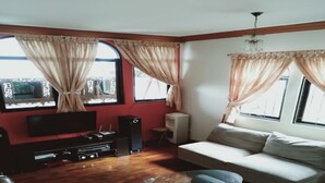 A living room with a sofa, TV, and entertainment system. - Villa Kota Bunga Vinca (Cipanas)