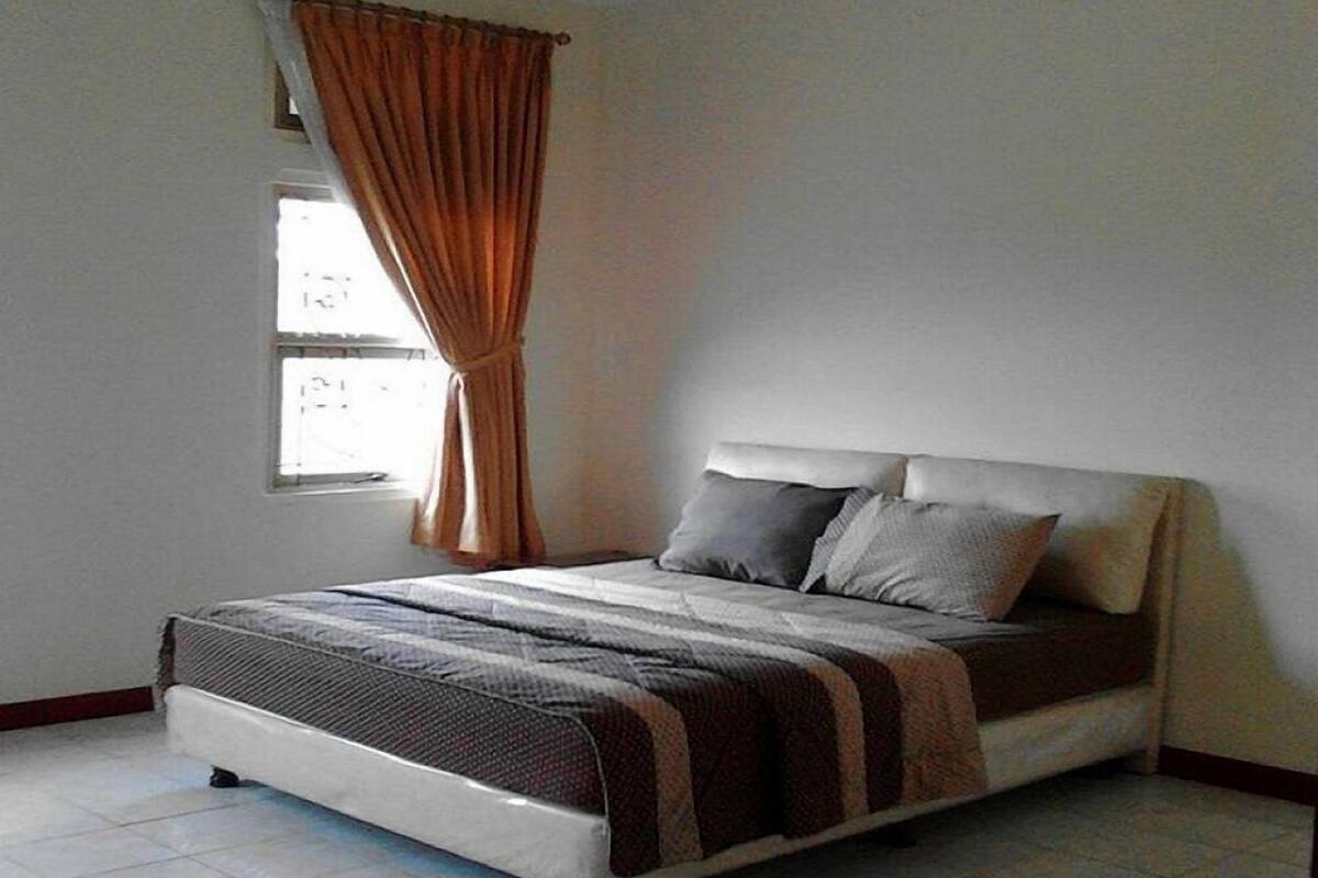 Un dormitori amb llit, cortines, una finestra i terra de rajola.