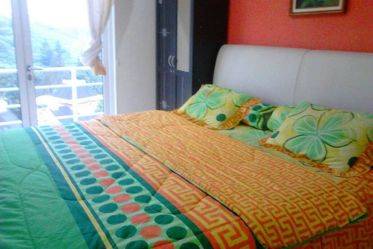 A bedroom with a bed, pillows, a wardrobe, and a window.