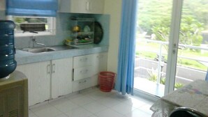 Una cocina con un lavamanos, armarios, dispensador de agua y una ventana con vistas a zonas verdes.