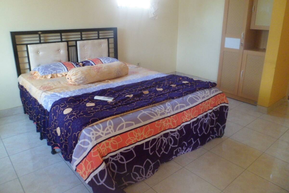 A bedroom with a bed, a wardrobe, and a window.