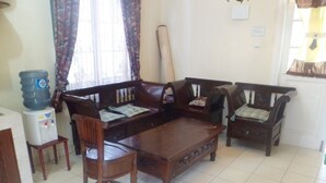 A living room with a sofa set, a coffee table, and a water dispenser. - Villa Kota Bunga Mawar (Cipanas)