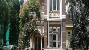 A historic building with a prominent arched window and decorative facade. - Villa Kota Bunga Peony (Cipanas)