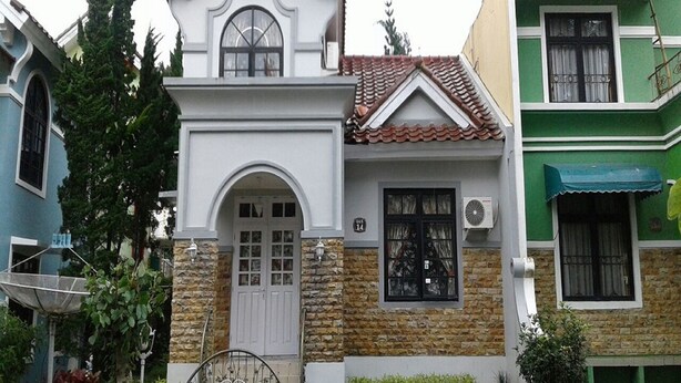Una casa de dos plantas con fachada blanca, sección inferior de piedra y tejado de tejas.