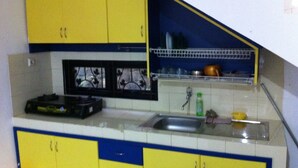 Una cocina con armarios amarillos, un lavamanos y una ventana con rejas decorativas de hierro.