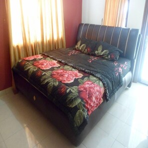 A bedroom with a bed, curtains, and a window. - Villa Kota Bunga Violet (Cipanas)