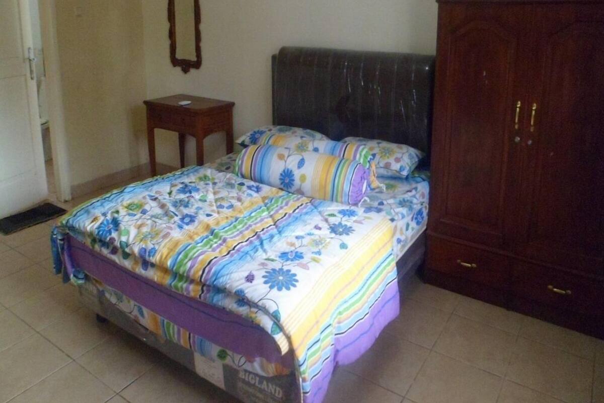 A bedroom with a bed, a small table, a mirror, and a wardrobe.