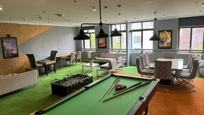 Ein stilvoller Aufenthaltsbereich mit Billardtisch, Kicker und bequemen Sitzgelegenheiten.