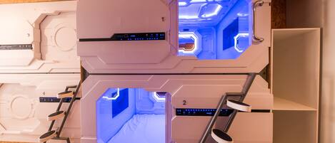 A futuristic room with two hexagonal viewing windows, a control panel, and a ladder.