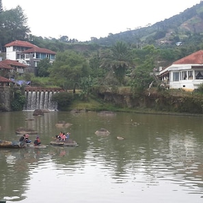 A river with people on elephants, a bridge, and buildings in the background.