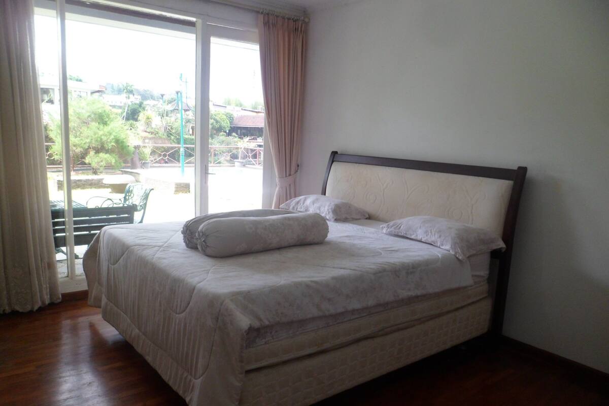 Une chambre à coucher avec un lit, une vue sur l’extérieur et une fenêtre avec des rideaux.