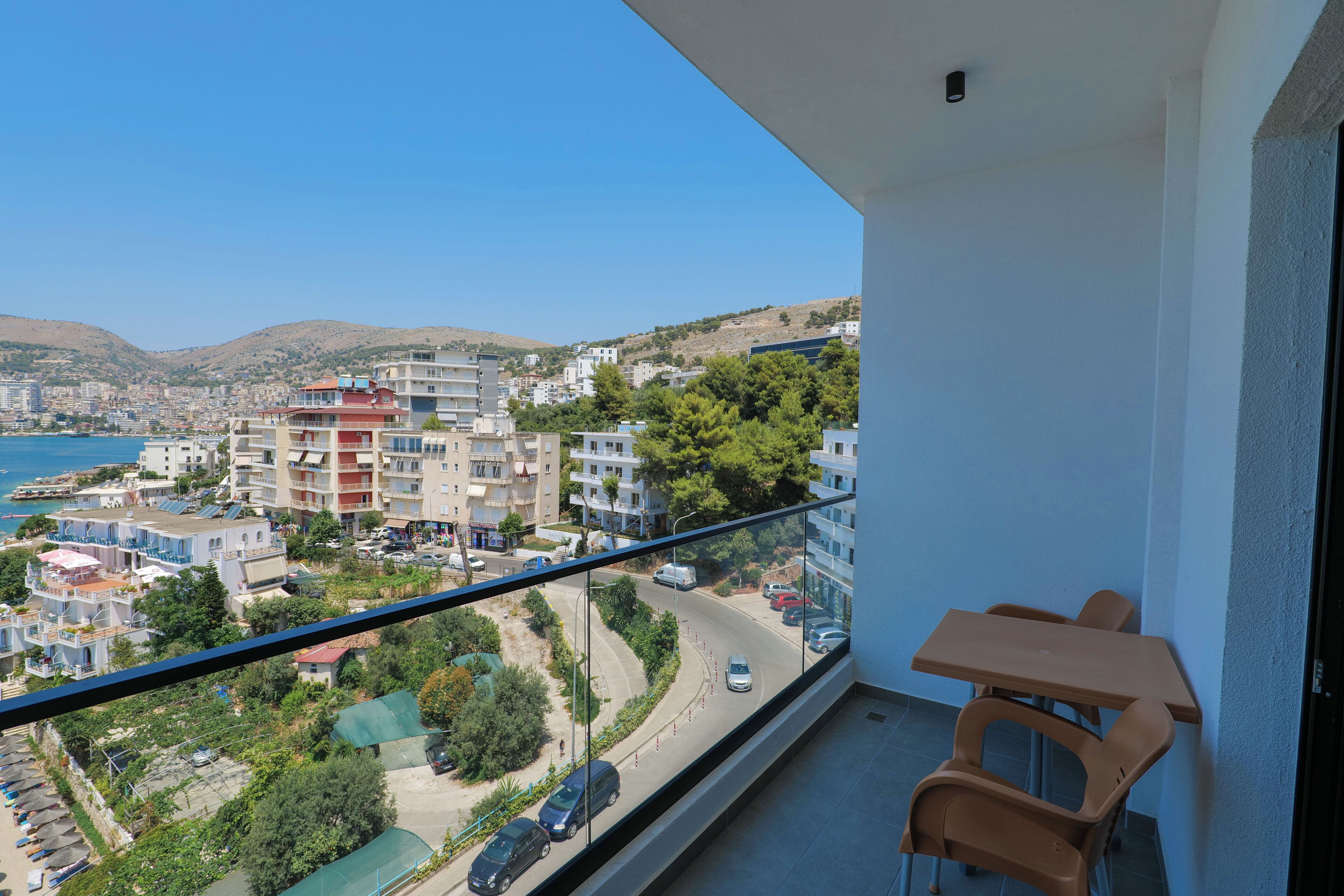 Un balcone con vista su una cittadina costiera, un tavolo e delle sedie.