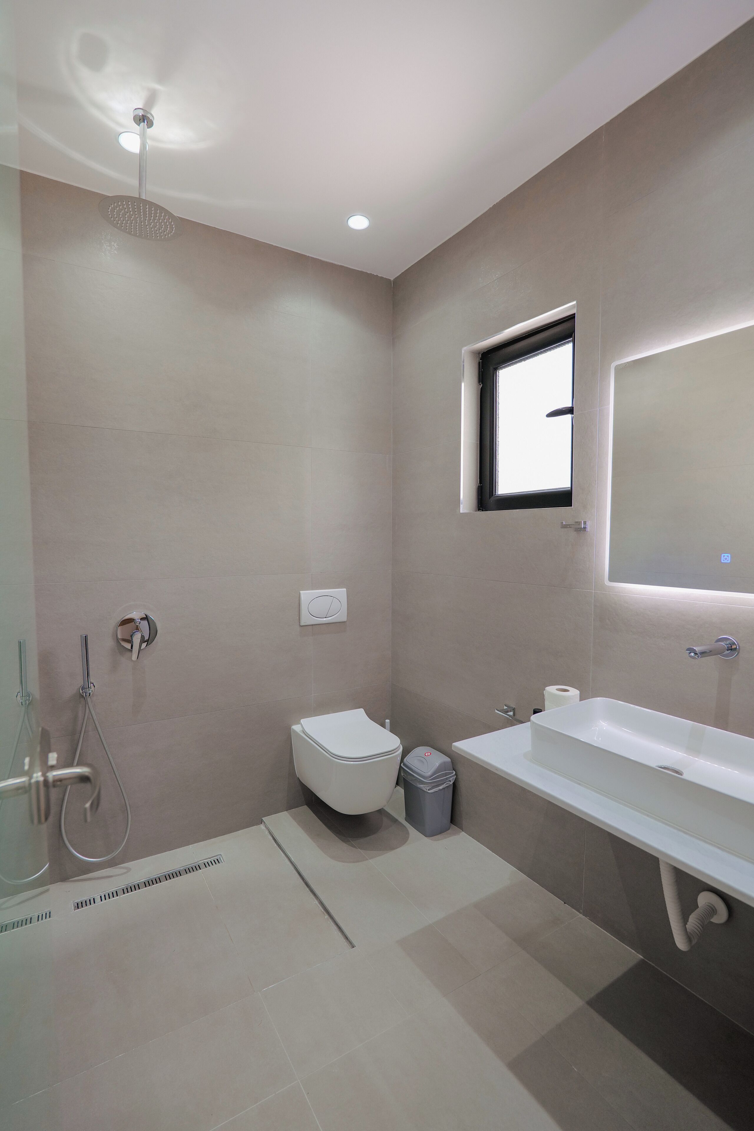 A modern bathroom with a shower, toilet, and sink.