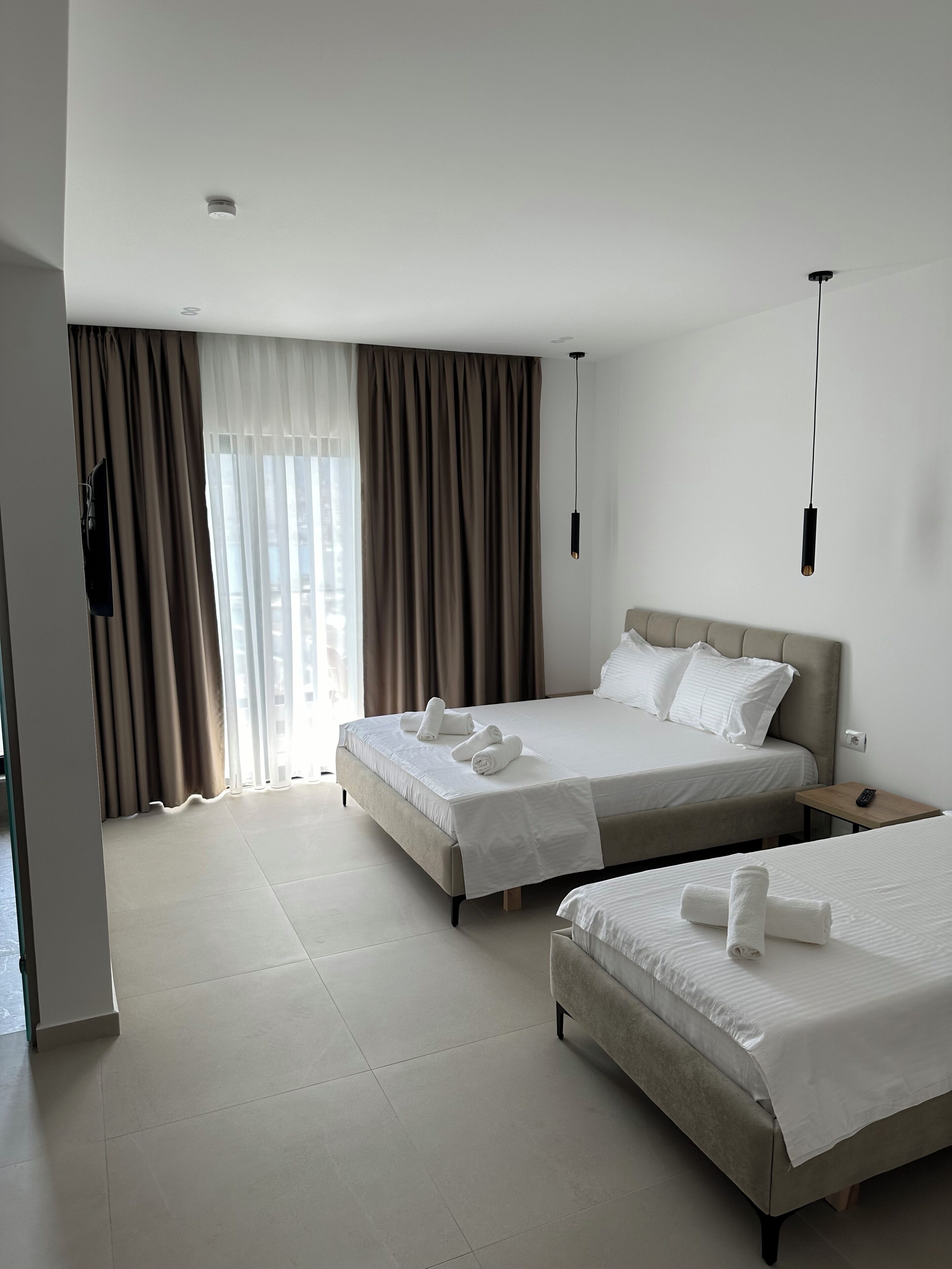 A hotel room with two beds, a TV, and a remote control on a nightstand.