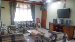 A living room with a sofa set, a coffee table, a television, and a cabinet. - Villa Private Puncak (Cipanas)